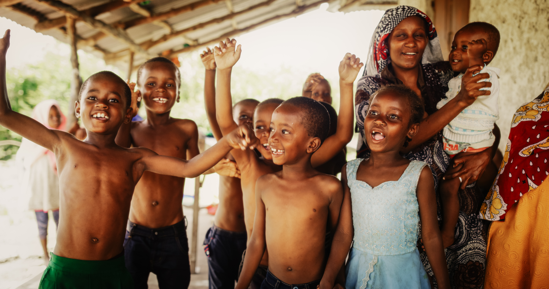 Children and a caregiver smiling together at an orphanage in Tanzania, Africa